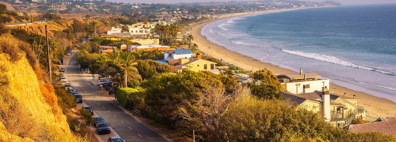 Uma estrada costeira com praia, oceano e casas.
