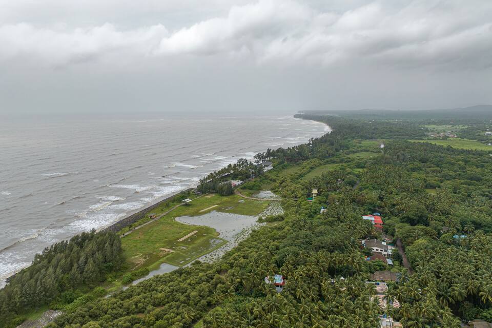 Un paysage côtier avec une plage, une végétation luxuriante et des bâtiments dispersés.