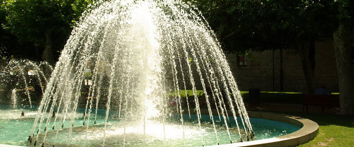 A circular fountain with multiple water jets in a park.