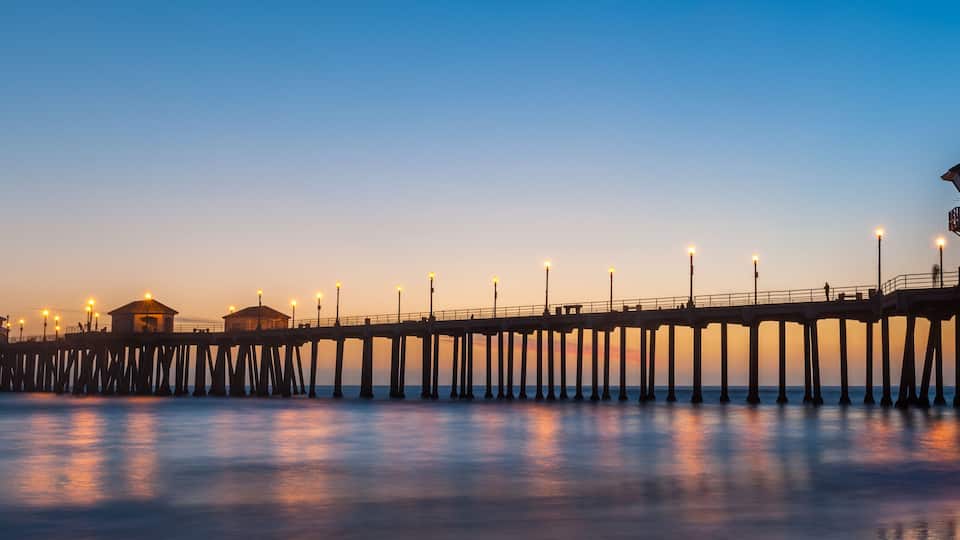 A pier extending into the water with a lighthouse and several buildings at the end.