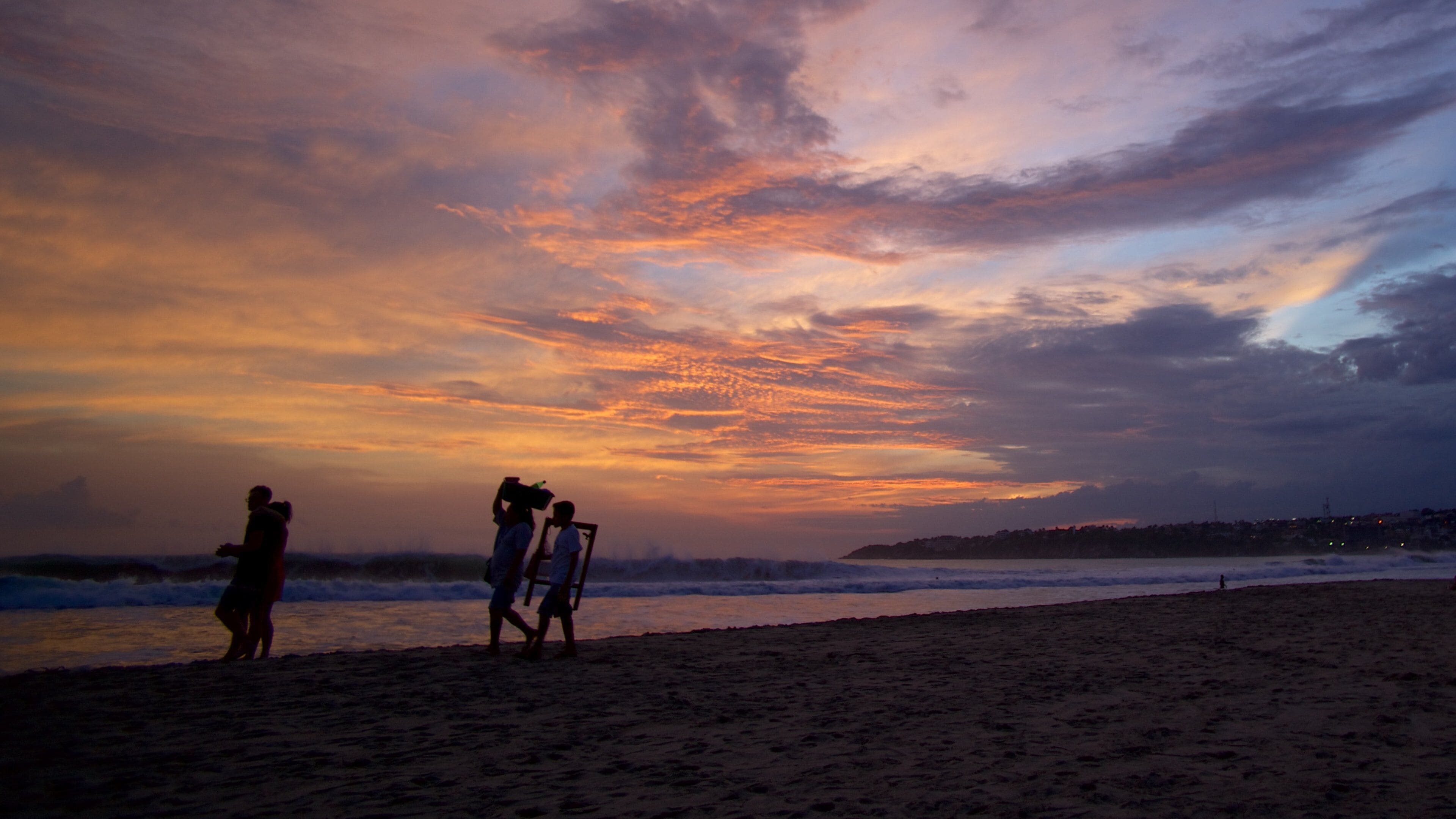Puerto Escondido showing a sunset and a beach as well as a small group of people