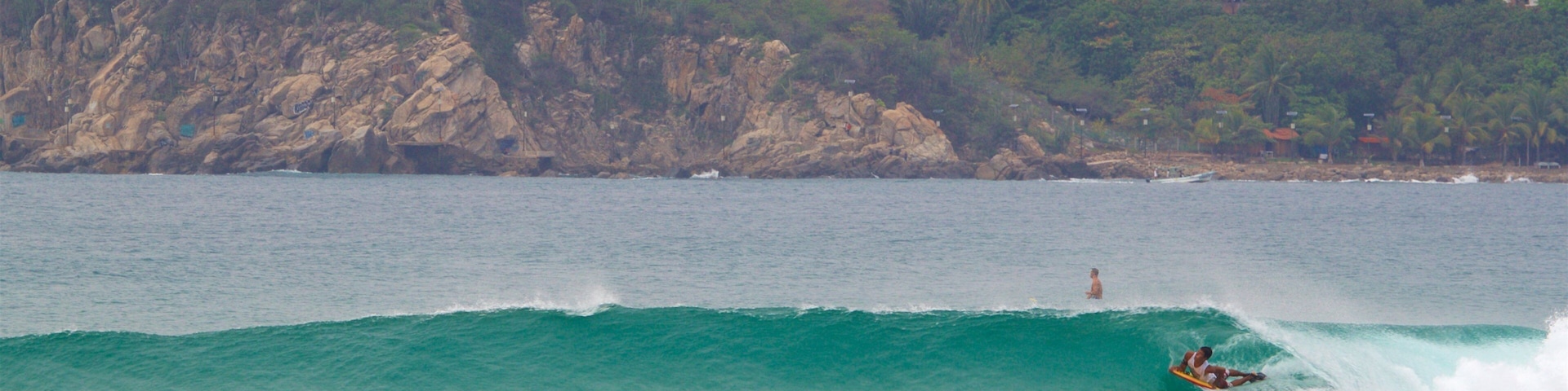 Zicatela Beach which includes waves, surfing and rocky coastline