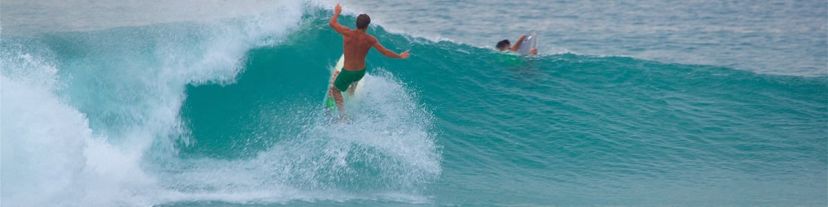 A surfer riding a wave in the ocean with another person in the water.