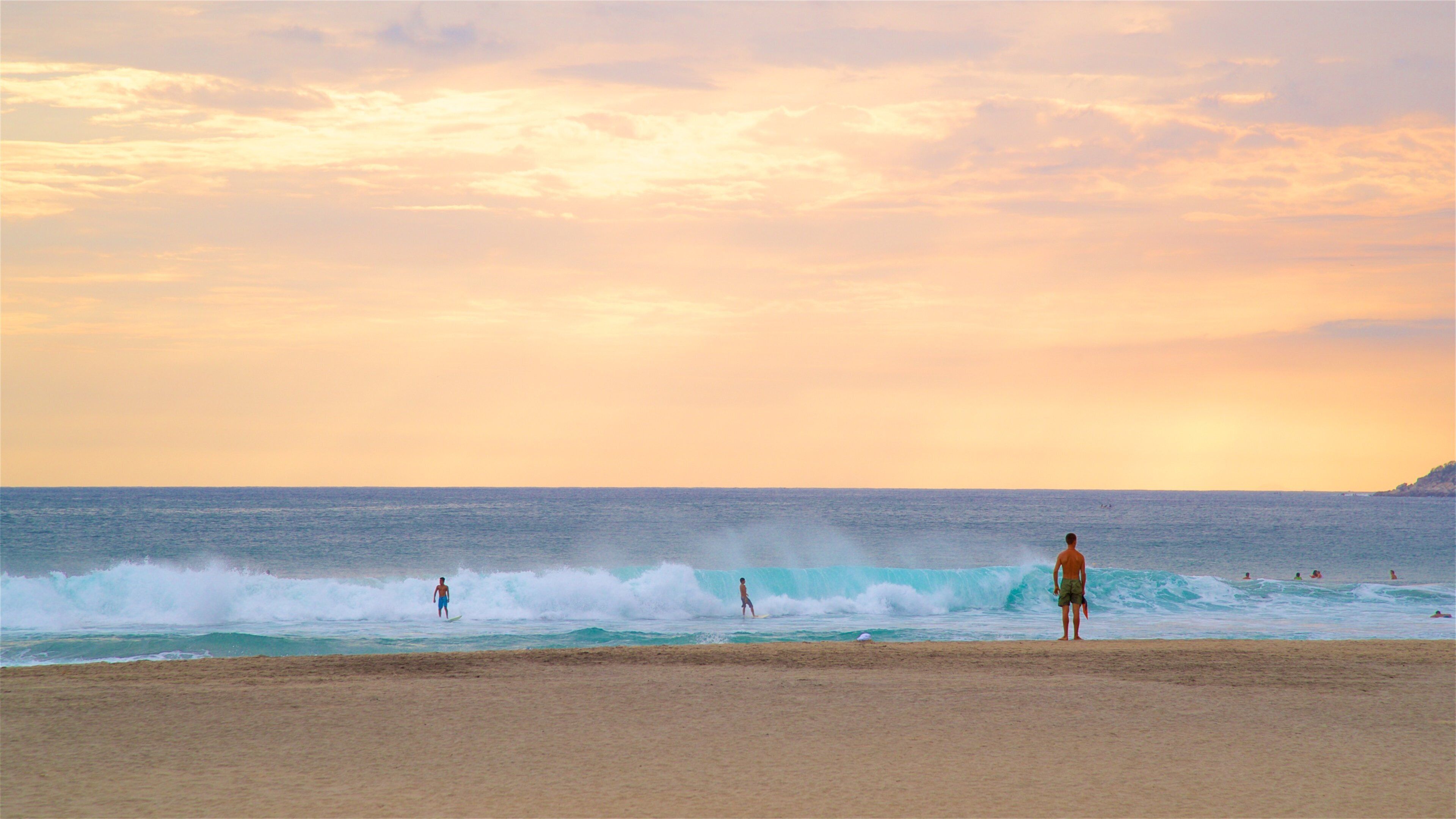 A beach with waves and a sunset.