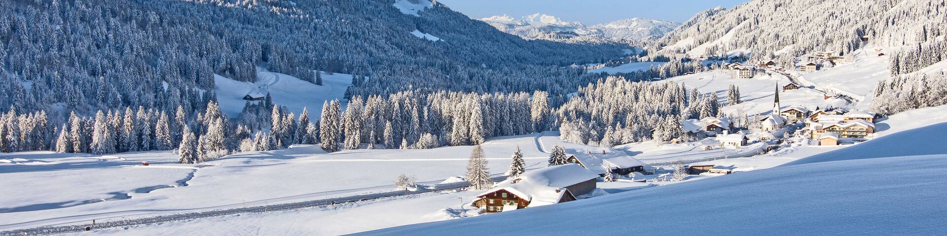 A snow-covered mountain landscape with a ski resort and buildings.