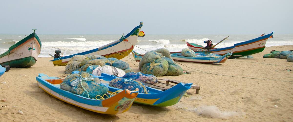 Several colorful fishing boats on a sandy beach with the ocean in the background.