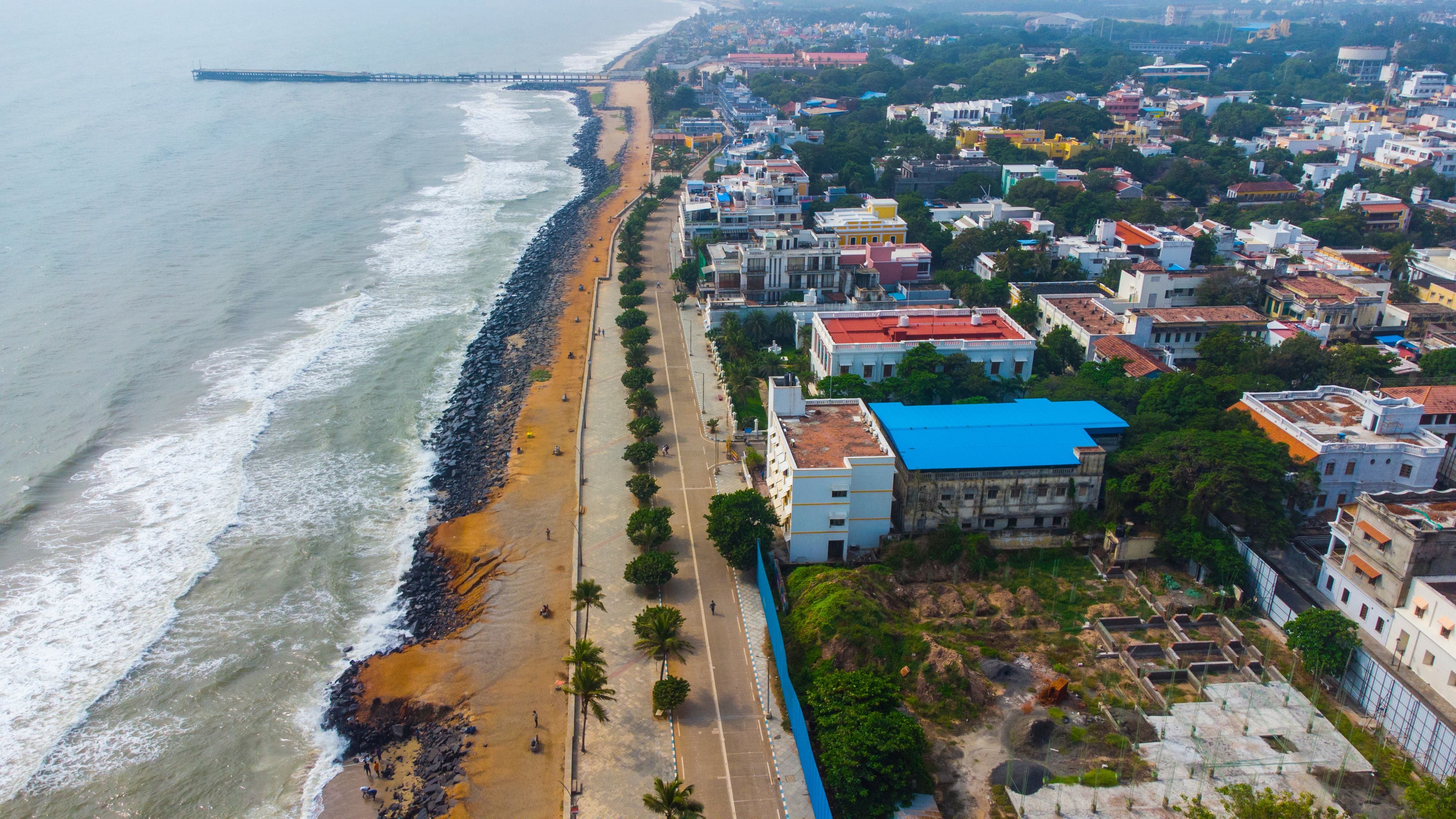 Un paisaje urbano costero con playa, un muelle y edificios muy juntos.
