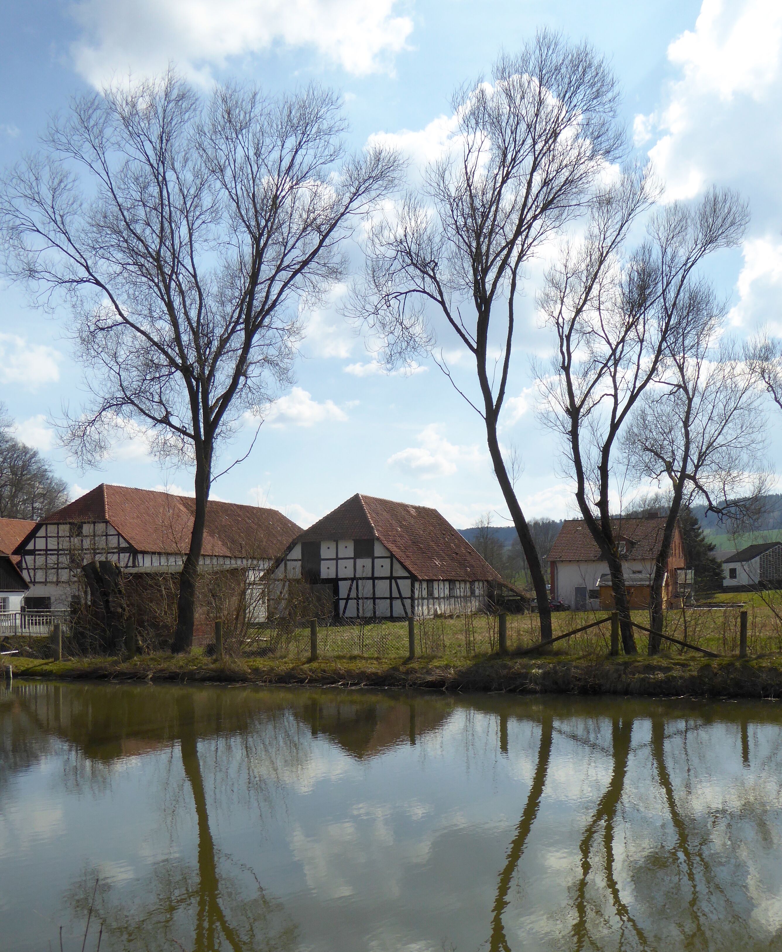 Üssinghausen, Stadt Hardegsen, Südniedersachsen. Vorn der Feuerlöschteich, hintenb Stellgebäude der ehemaligen Domäne