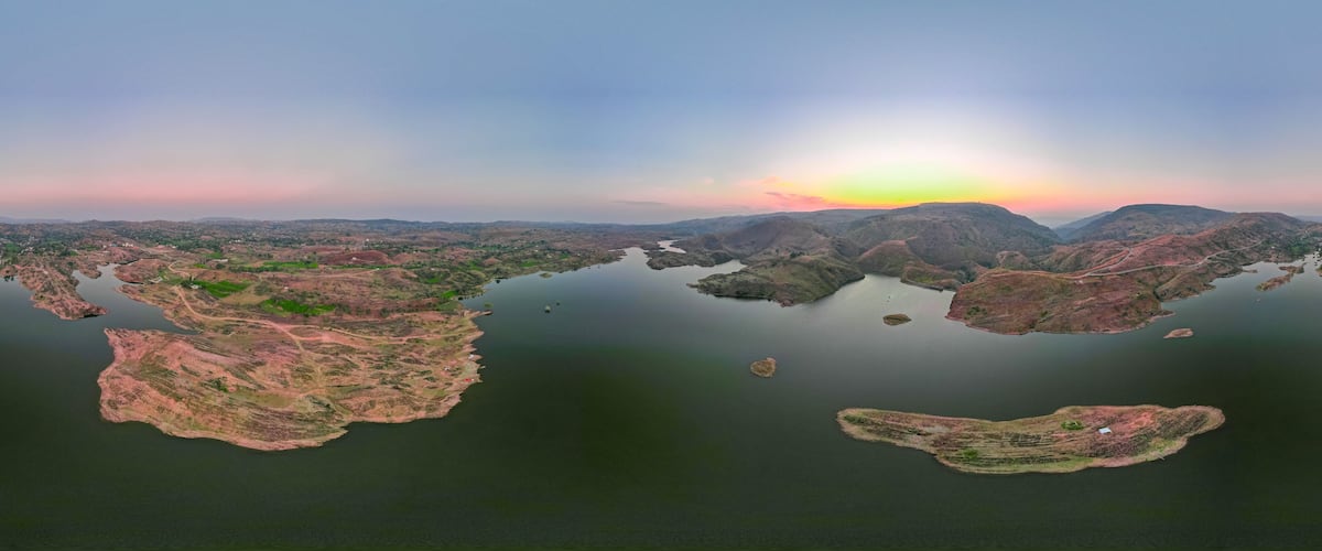 A panoramic view of a lake surrounded by hills and small islands.