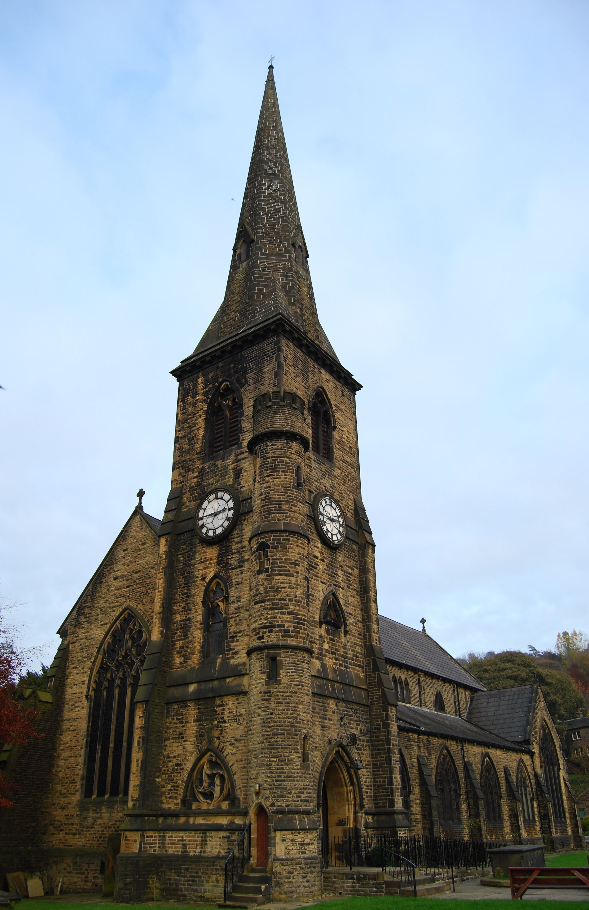 A historic church with a tall spire, two large clocks, and arched windows.