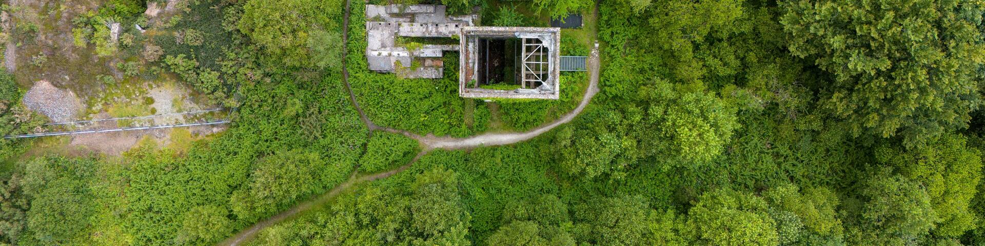 Aerial view of the ruins of a cornish mining heritage site surrounded by lush forest and greenery, Gunnislake, United Kingdom.