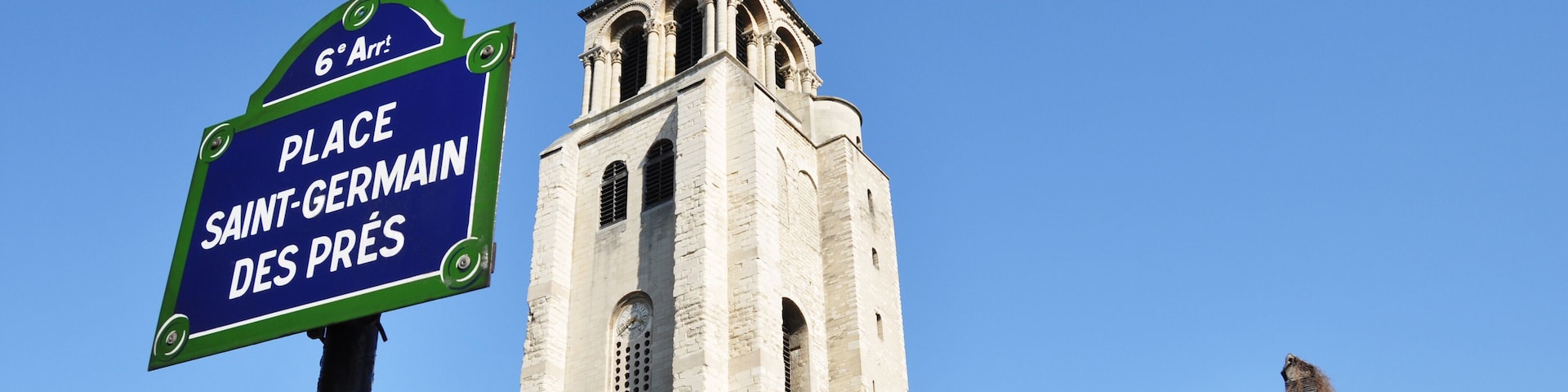 Una iglesia con un alto campanario y un cartel que indica 'Place Saint-Germain des Prés'.