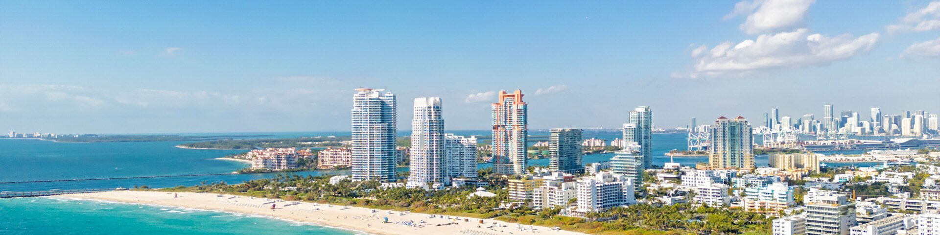 Un paisaje urbano costero con playa, aguas azules cristalinas y edificios altos.