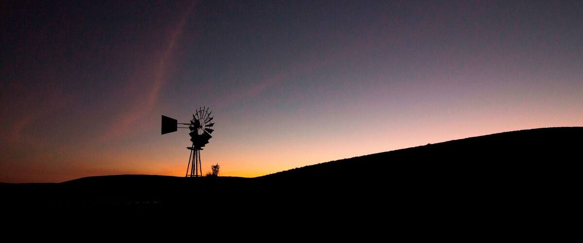 A windmill silhouetted against a sunset sky.