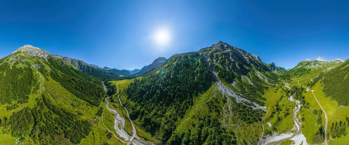 A mountain landscape with a clear sky and a winding road through a valley.