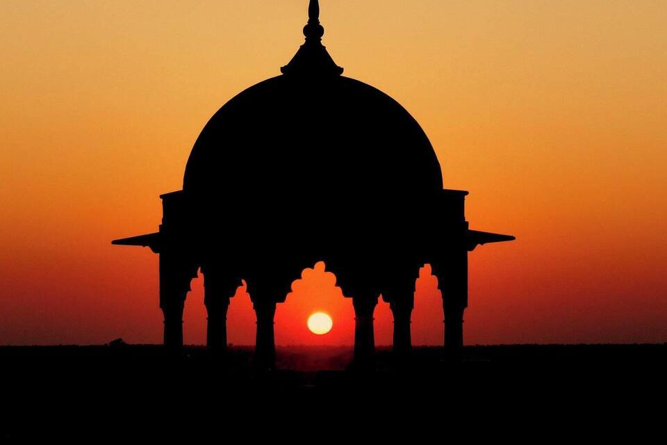 A silhouette of a domed structure against a sunset sky.