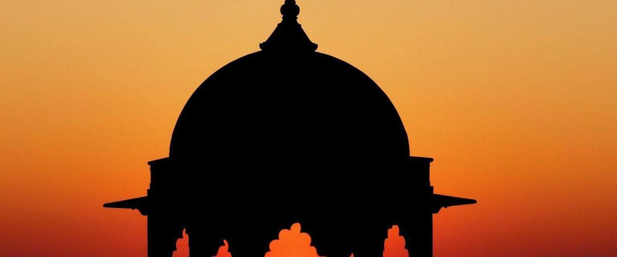 A silhouette of a domed structure against a sunset sky.