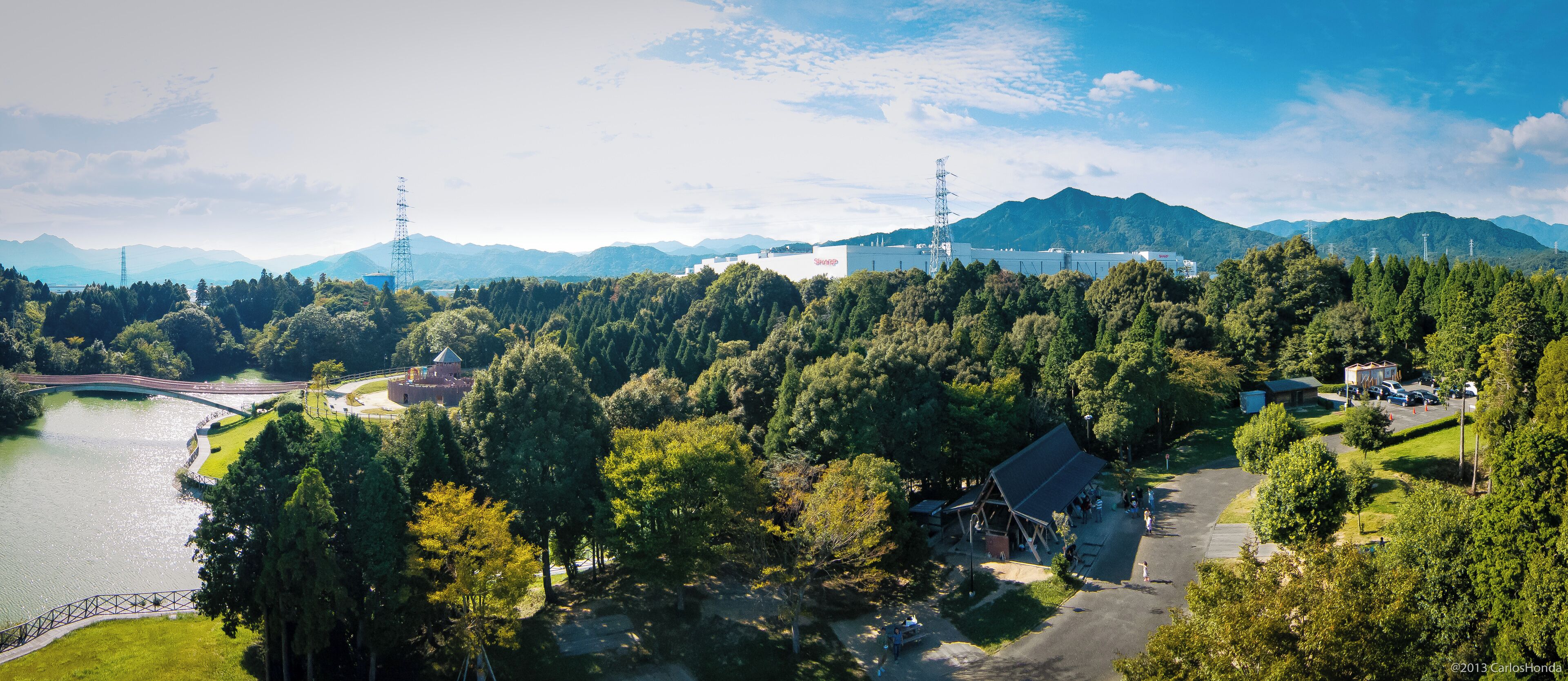 A mountainous landscape with a lake, a bridge, and a building with a red roof.