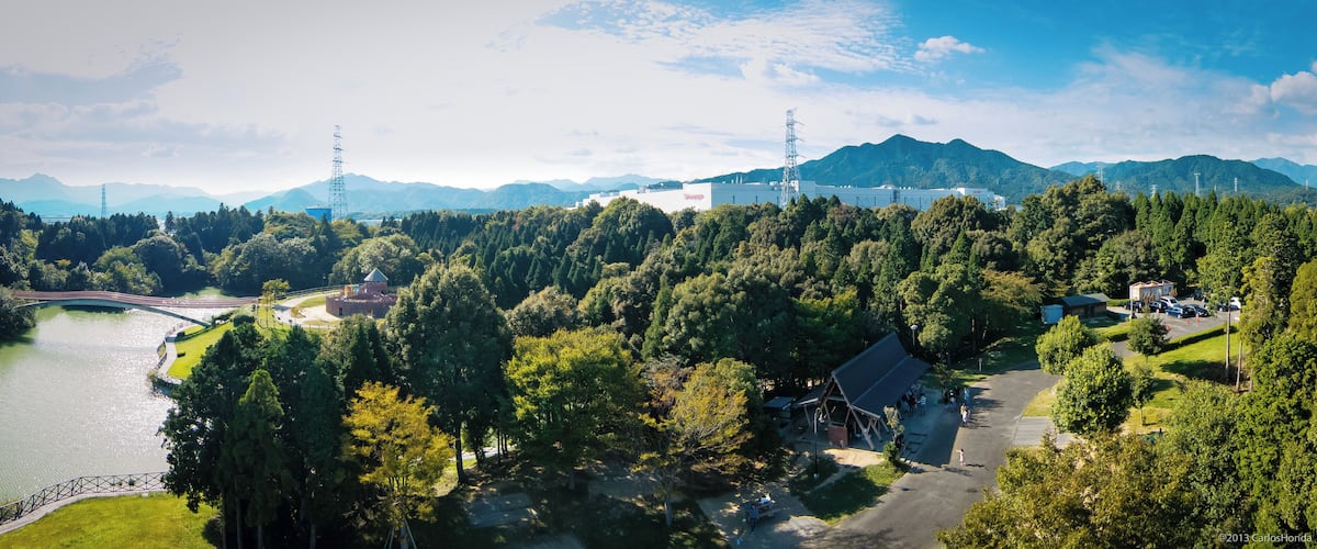 A mountainous landscape with a lake, a bridge, and a building with a red roof.