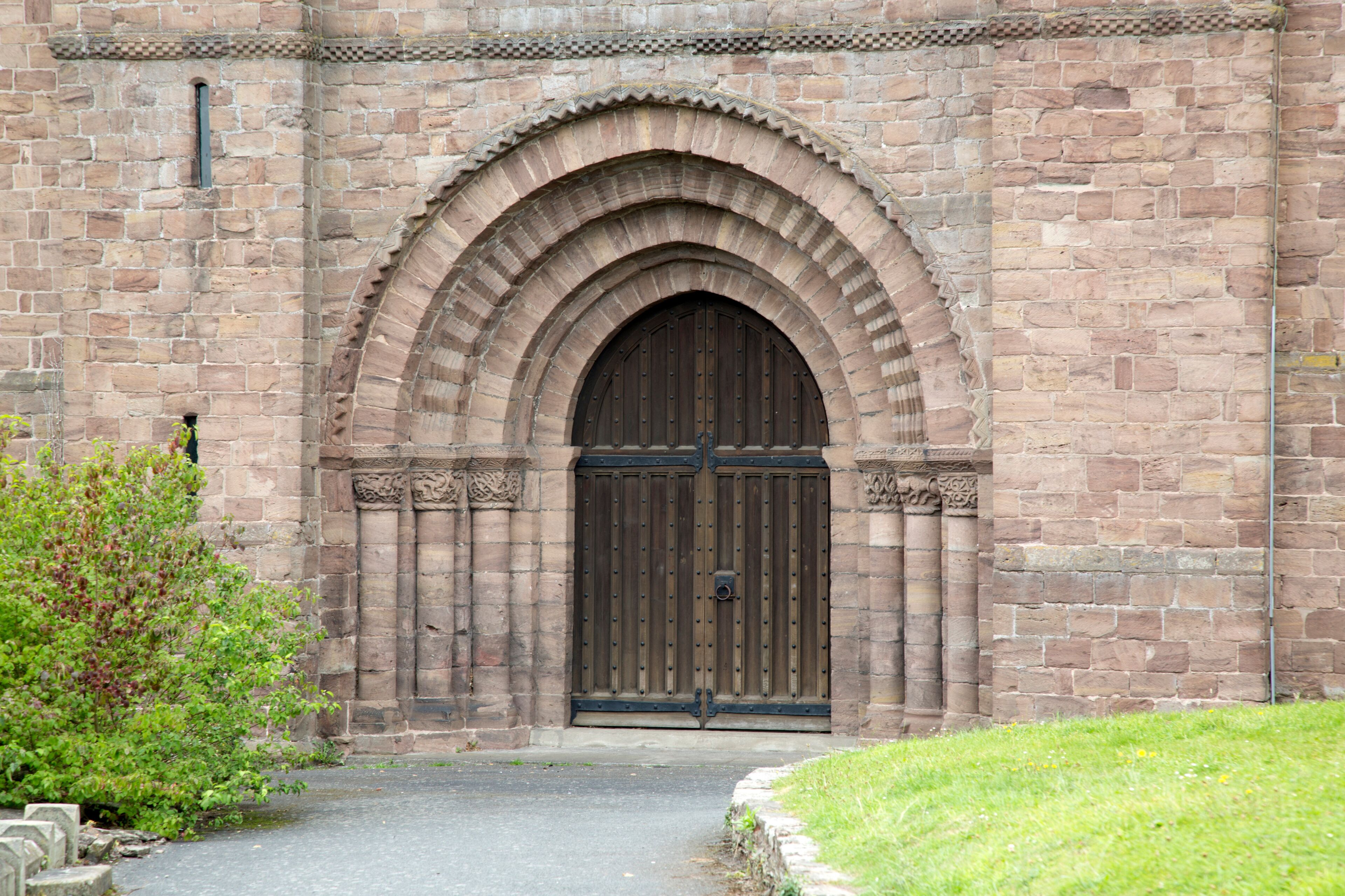 A stone building with a large arched entrance and a wooden door.
