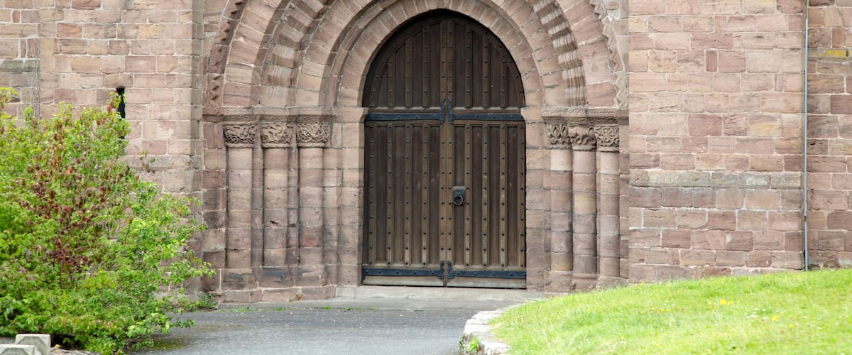 A stone building with a large arched entrance and a wooden door.