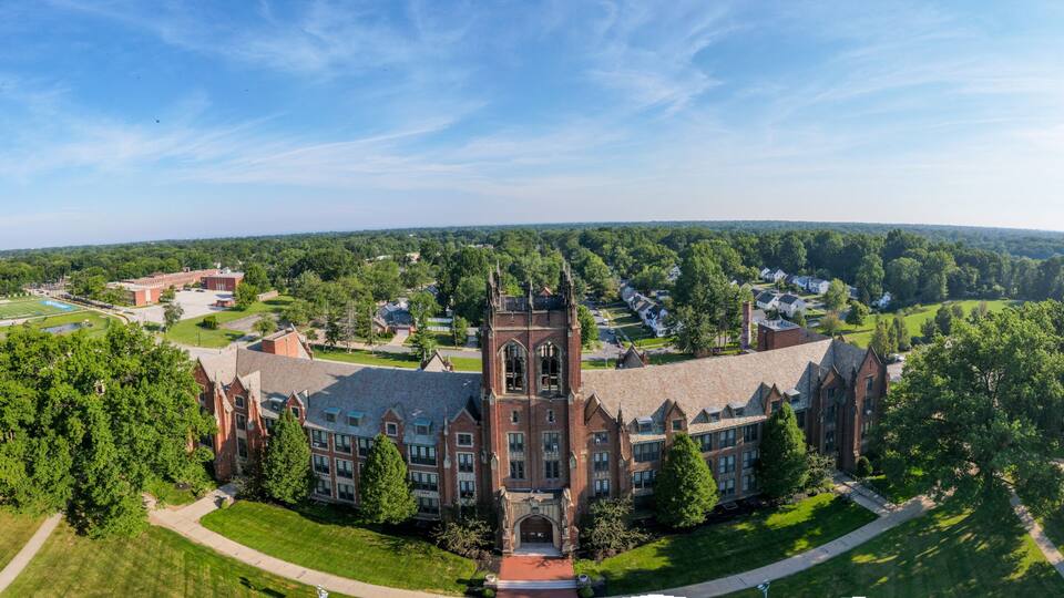 A large campus with a prominent Gothic-style building, surrounded by green lawns and trees.