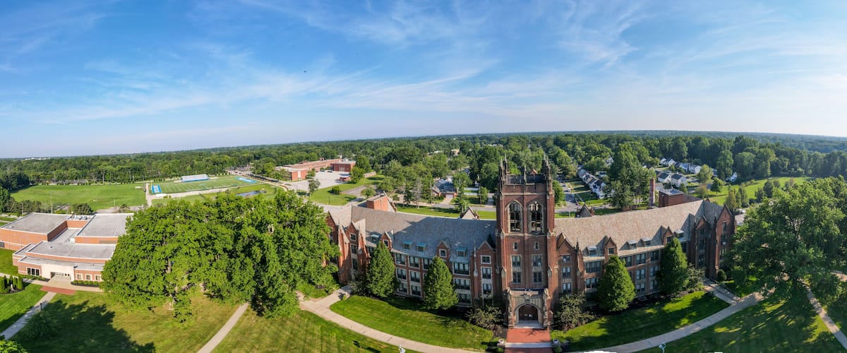 A large campus with a prominent Gothic-style building, surrounded by green lawns and trees.