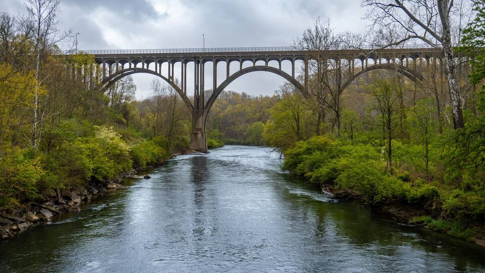 A stone bridge over a river surrounded by trees.
