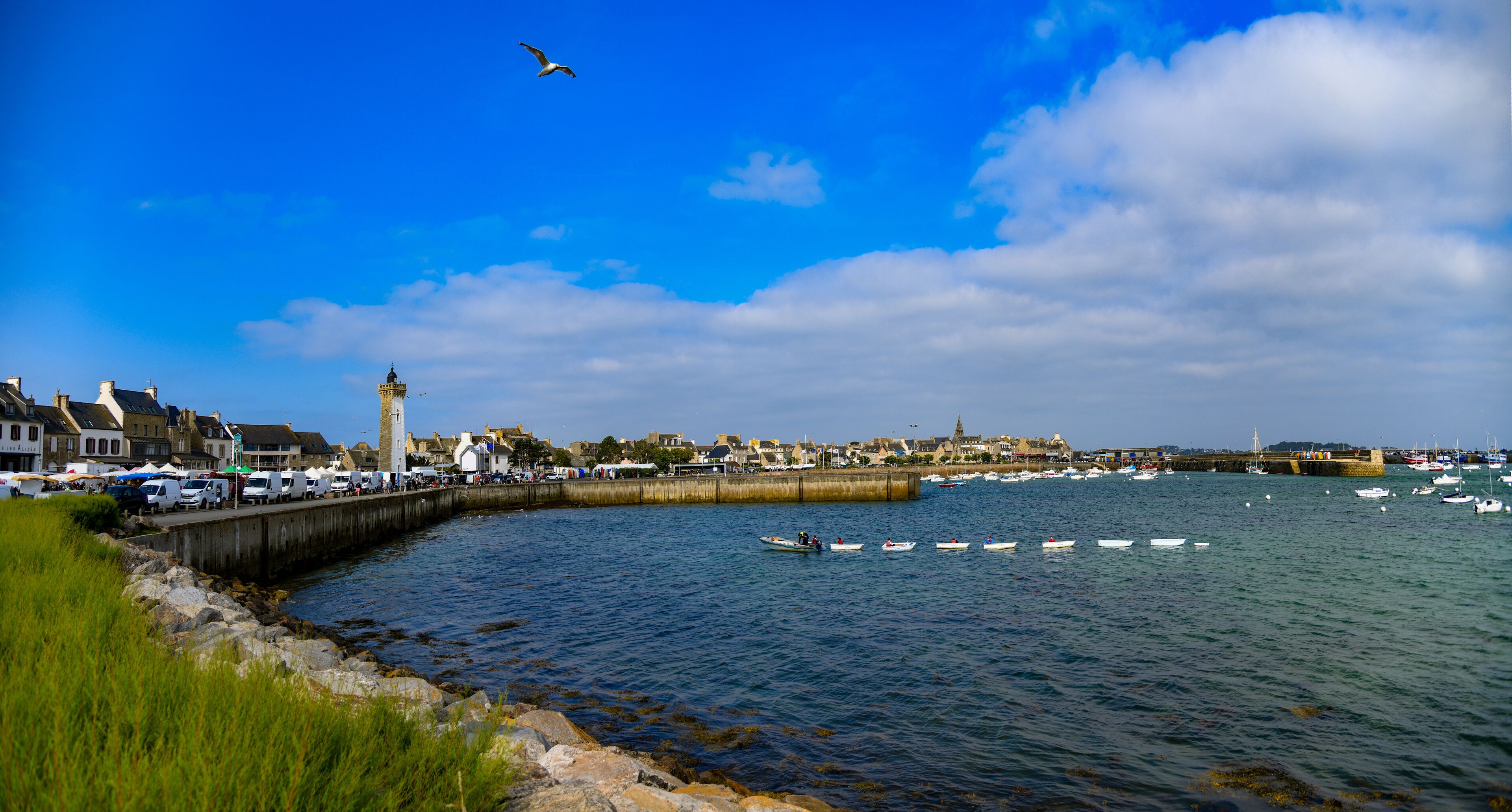 Un puerto con barcos, un faro y un pueblo costero.