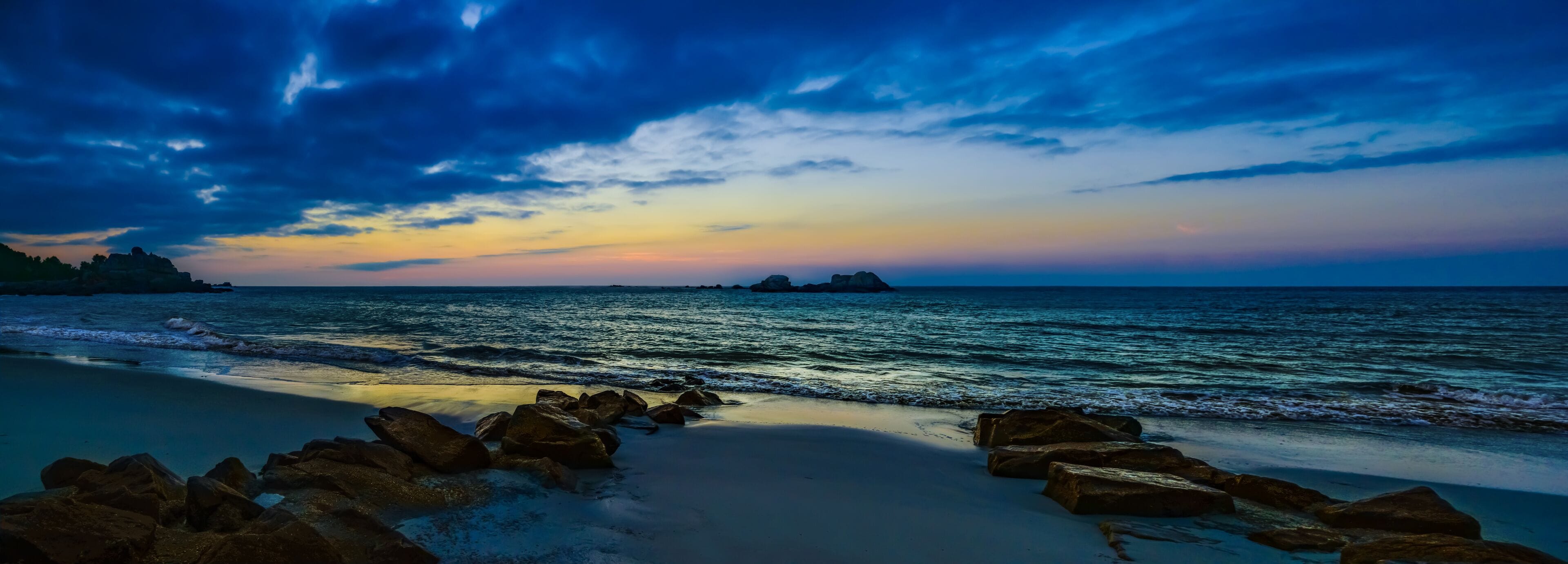 Panorama ciel et mer nuit tombante avec rochers en 1er et arrière-plan