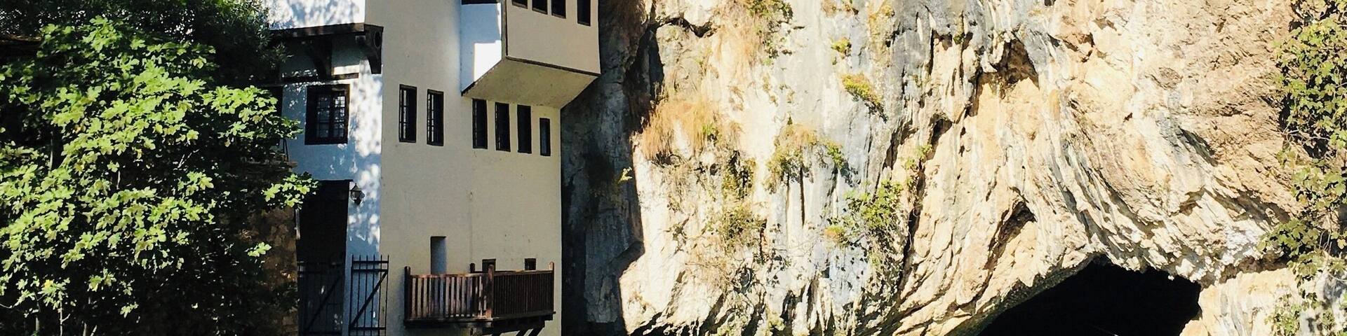 A house built into a cliffside with a clear water body in front.