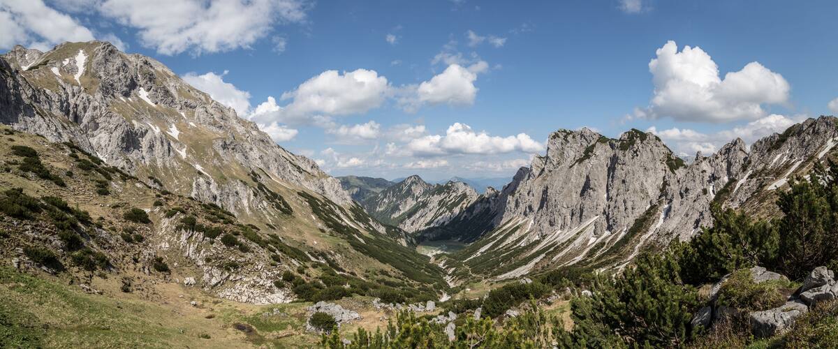 A mountainous landscape with rocky peaks, a valley, and scattered greenery.