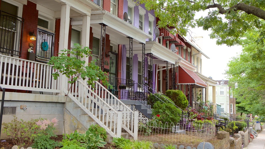 A row of colorful Victorian-style houses with ornate balconies and a well-maintained garden.