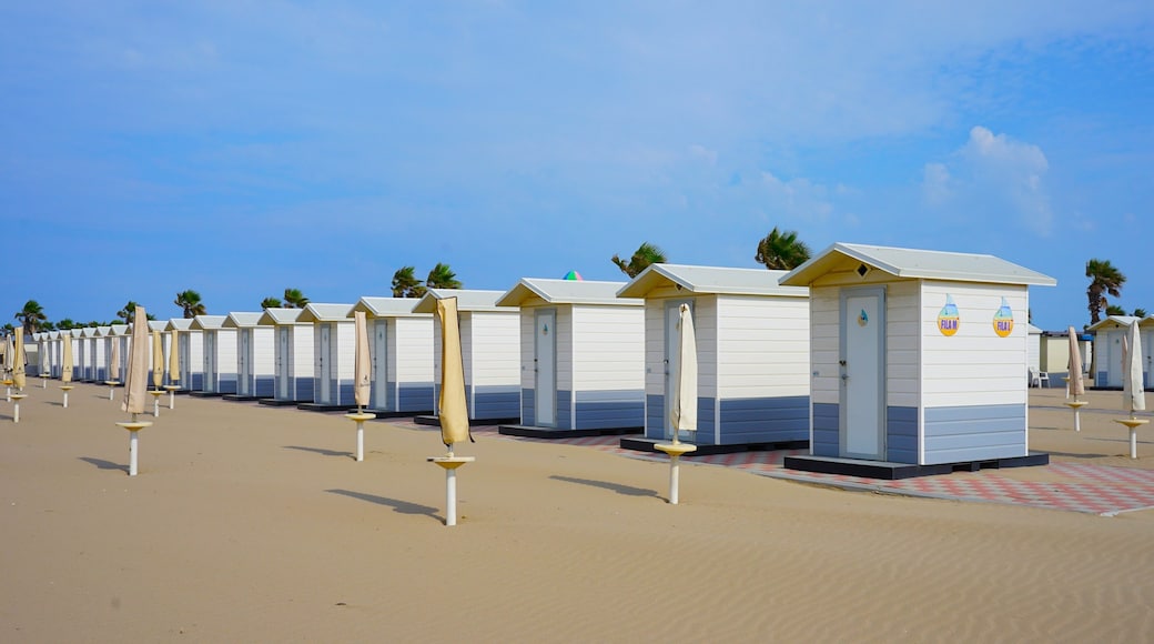 A row of beach huts with umbrellas on a sandy beach.