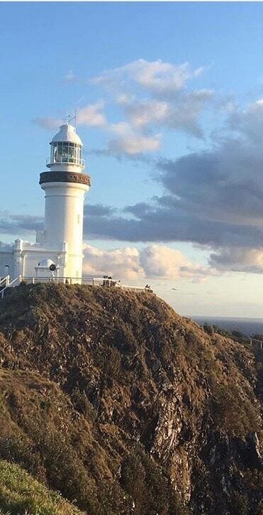 A lighthouse on a rocky hill with a clear sky.