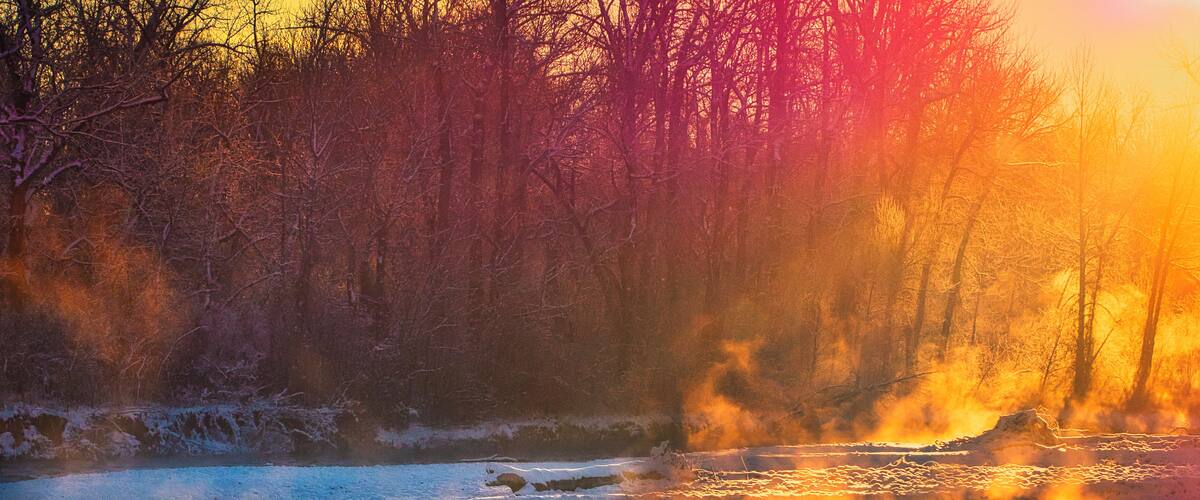 A river with a reflection of trees and a sunset.