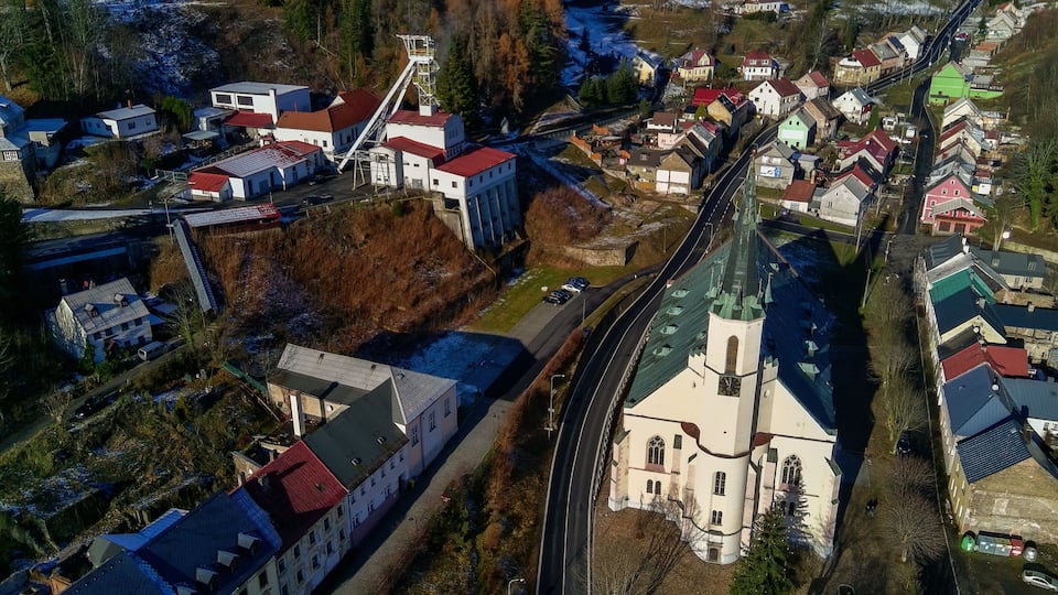 An aerial view of a town with a church, residential buildings, and a large industrial facility.