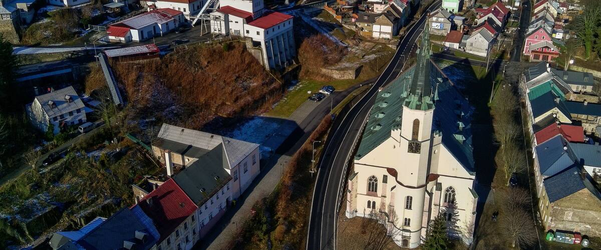 An aerial view of a town with a church, residential buildings, and a large industrial facility.