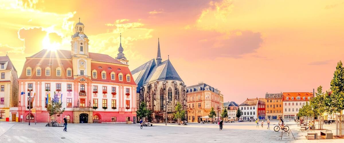 A historic square with a prominent church, colorful buildings, and a clear sky.