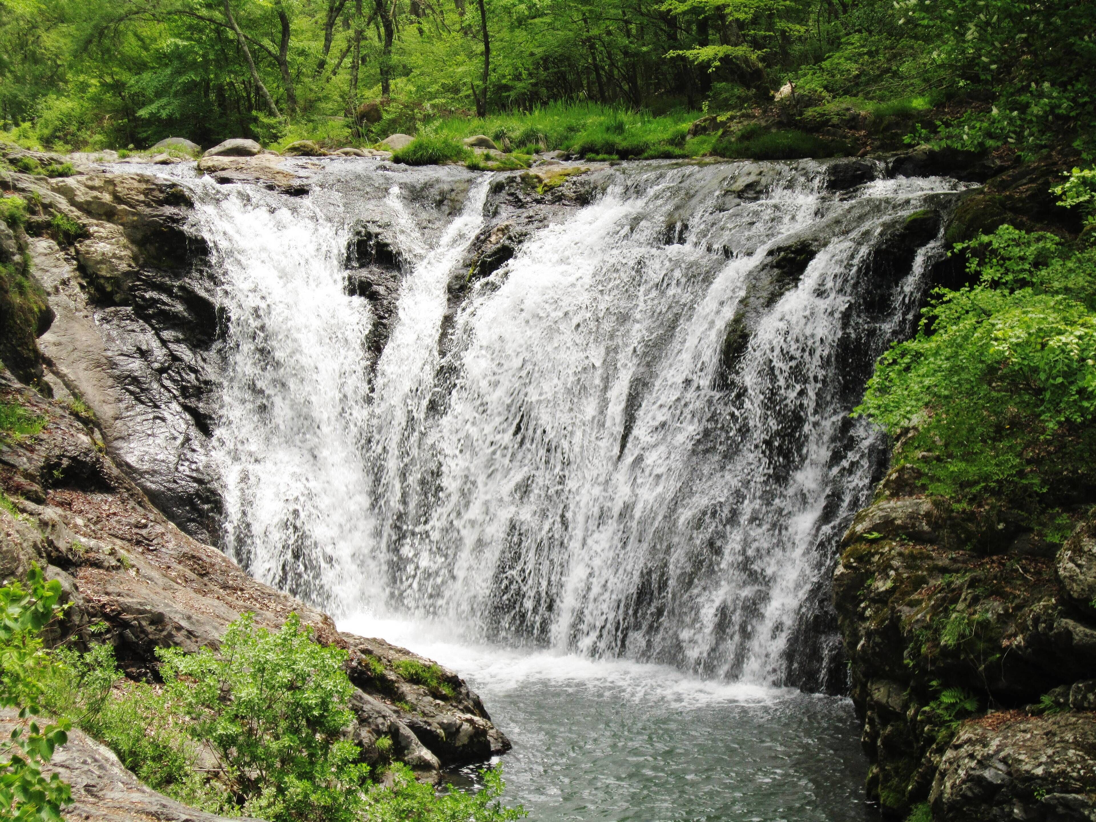 A multi-tiered waterfall surrounded by lush greenery.