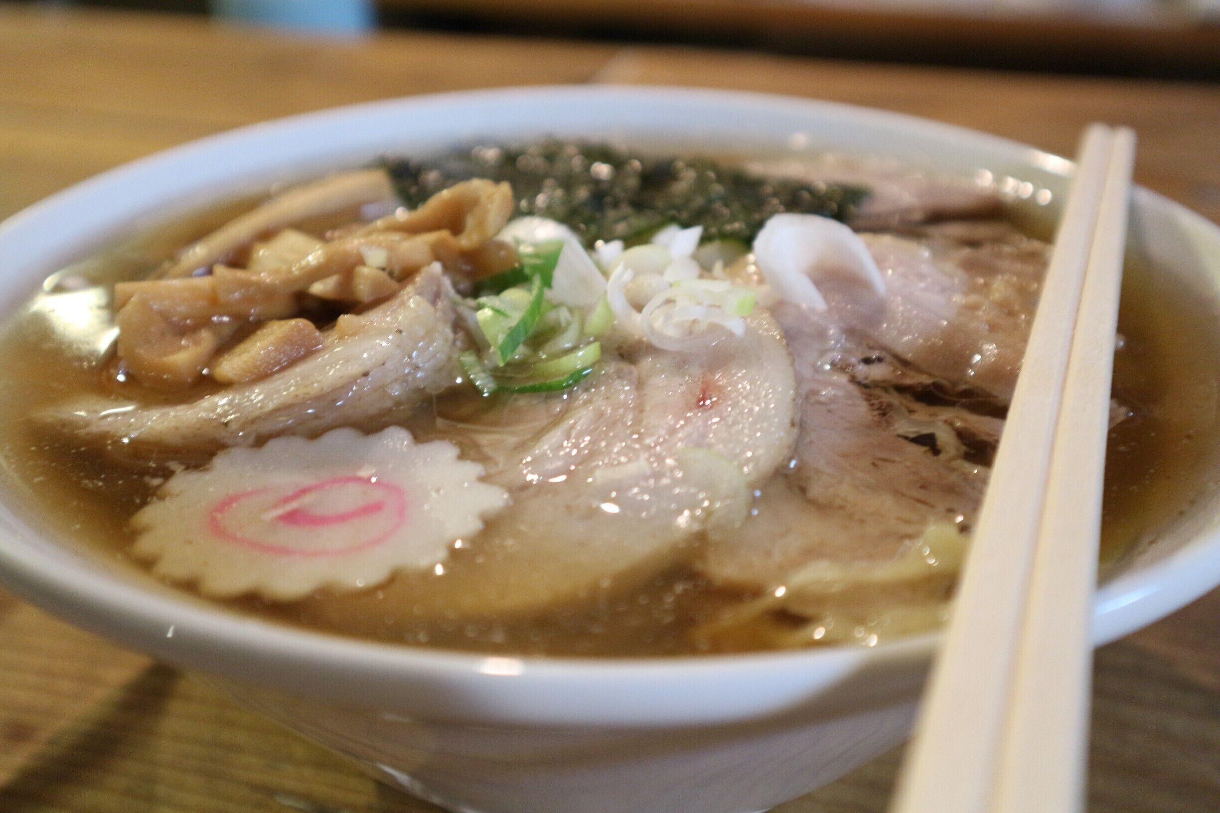 A bowl of soup with meat, vegetables, and seaweed.
