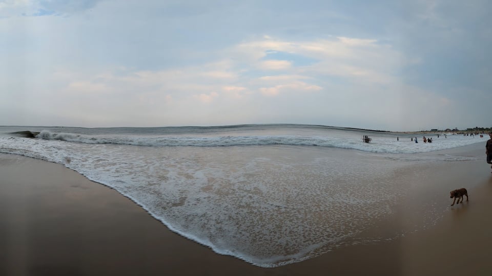 A serene evening at Rushikonda Beach, in Andhra Pradesh, India, with soft golden hues from the setting sun reflecting on the calm, blue waters.