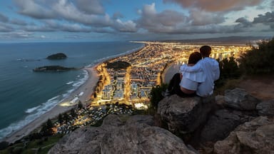 A couple climbed to the top of Mount Maunganui to view the city of Tauranga, New Zealand. The view at night time is simply mesmerizing. There are beautiful lights coming from the roads and buildings.