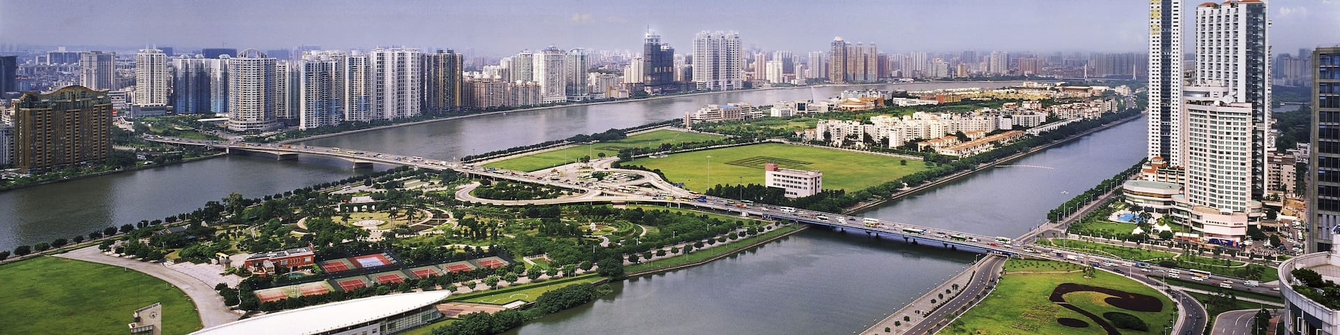 A river flowing through a city with high-rise buildings, a bridge, and green spaces.