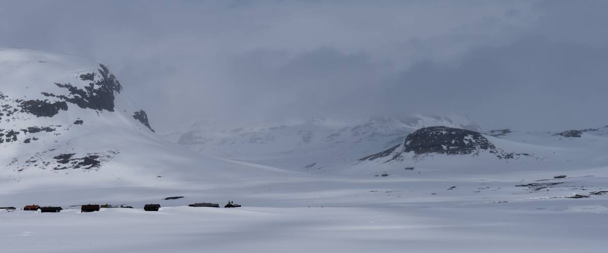 A snowy mountain landscape with several buildings.