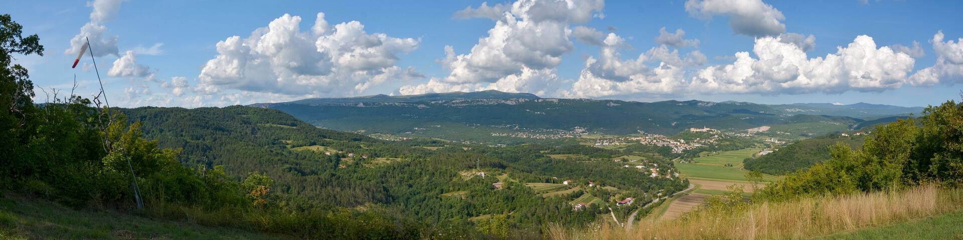 Panorama shot of the city of Buzet in Istria with green mountains, blue sky and white clouds