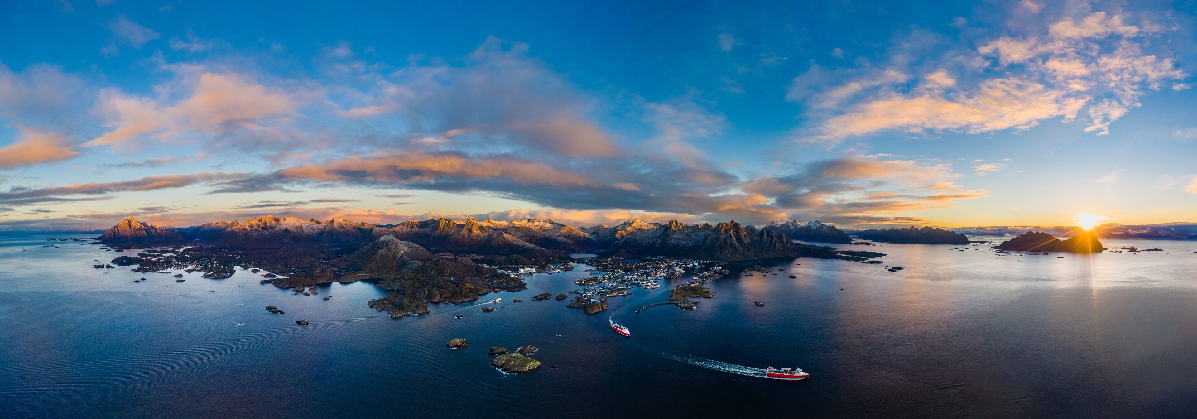 A panoramic view of a fjord with a red ship navigating through calm waters, surrounded by rugged mountains and a sunset.