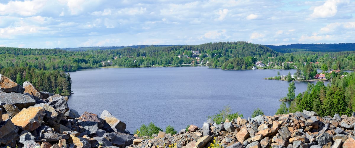 A lake surrounded by forested hills and rocky terrain.