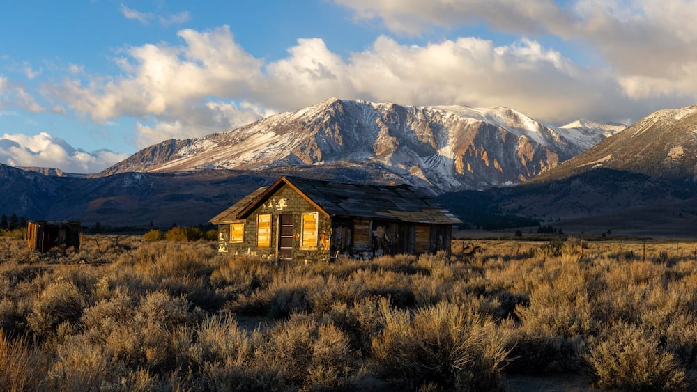 Abandoned old house at sunrise in front of the California Sierra Nevada mountains