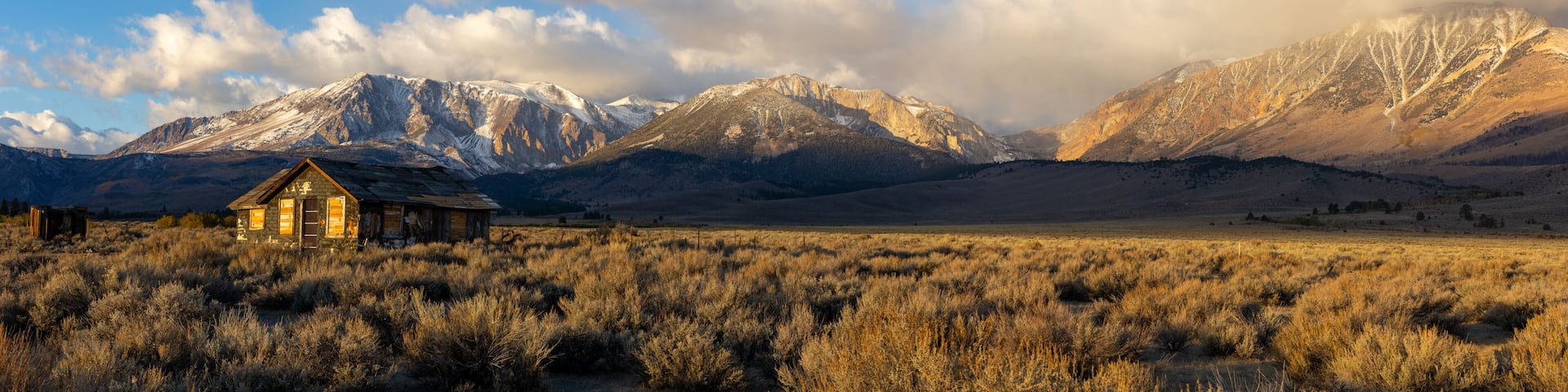 Abandoned old house at sunrise in front of the California Sierra Nevada mountains